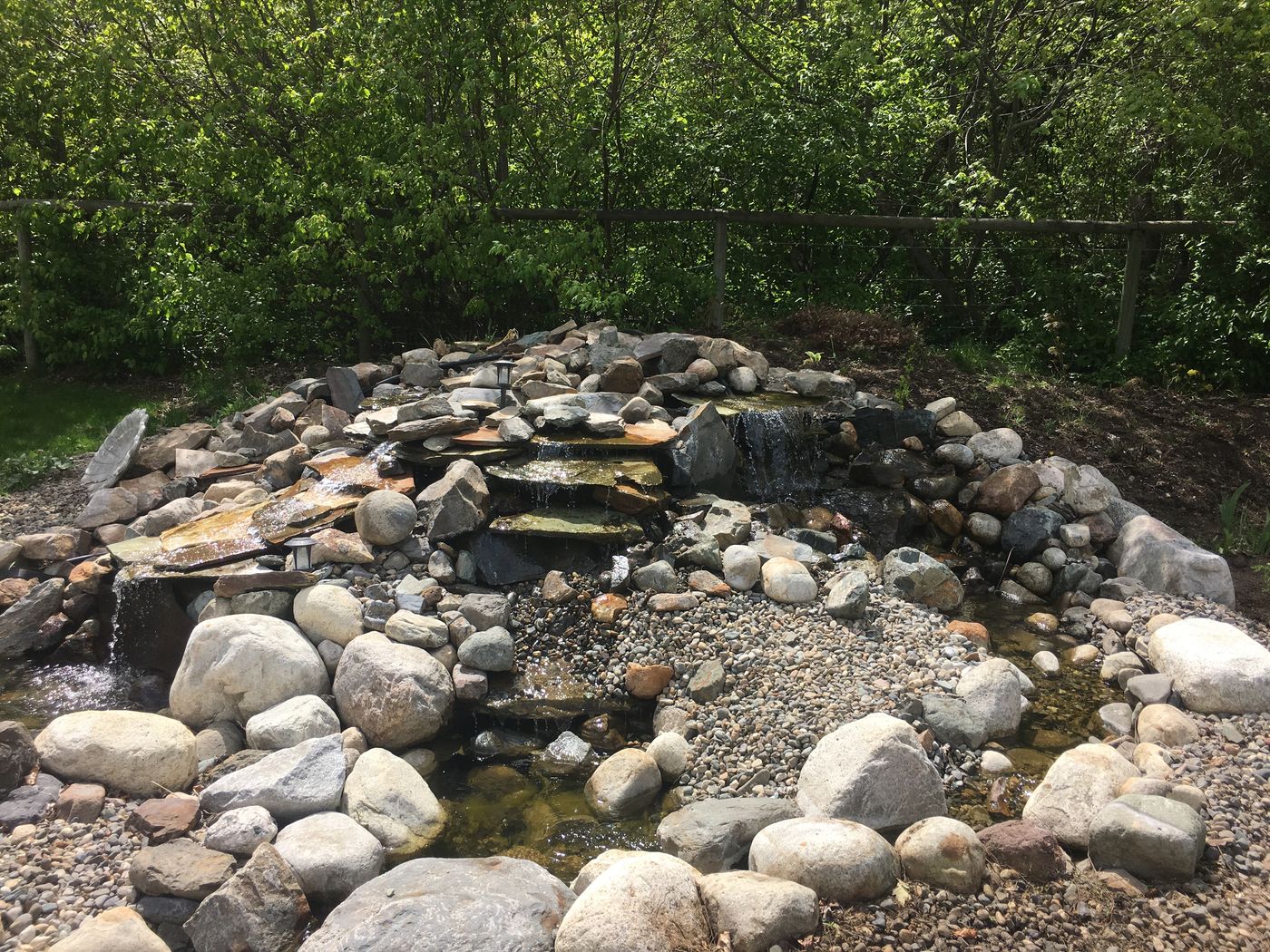 Stacked stone waterfall surrounded by river rock